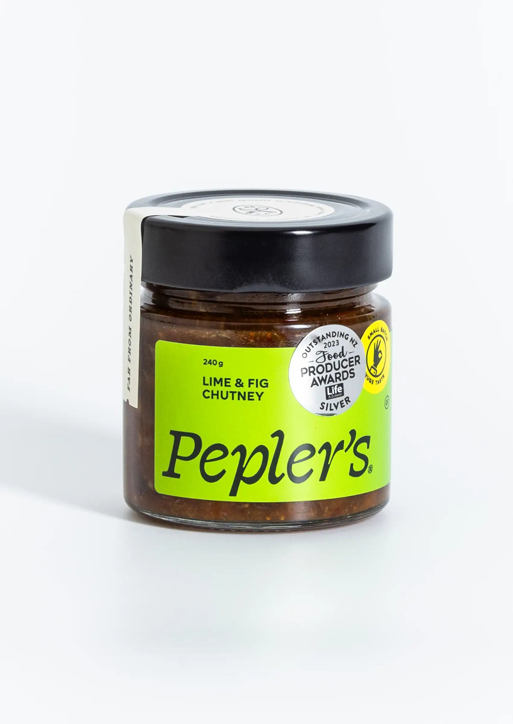 A clear jar of Pepler's Lime & Fig Chutney, weighing 240 grams, prominently displayed with a bright green label. The label features bold black text and a logo indicating an award for outstanding produce from 2021. The product has a black lid and is set against a light background, highlighting its contents.