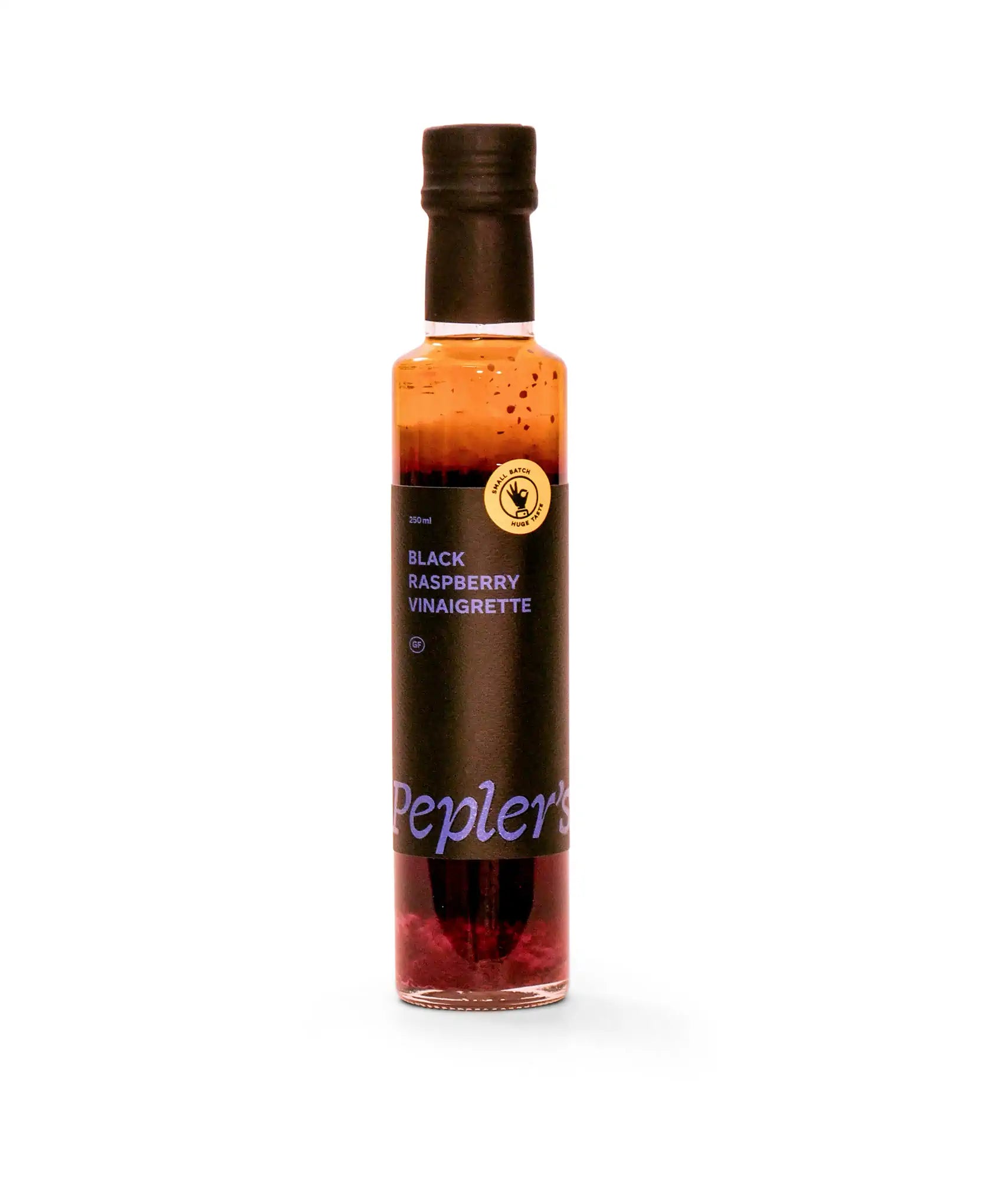 A bottle of Pepler's black raspberry vinaigrette, featuring a dark label with white and blue text. The bottle has a black cap and displays a small badge indicating it is a small batch product. The vinaigrette appears rich and dark, with visible raspberry particles at the bottom, set against a plain white background.