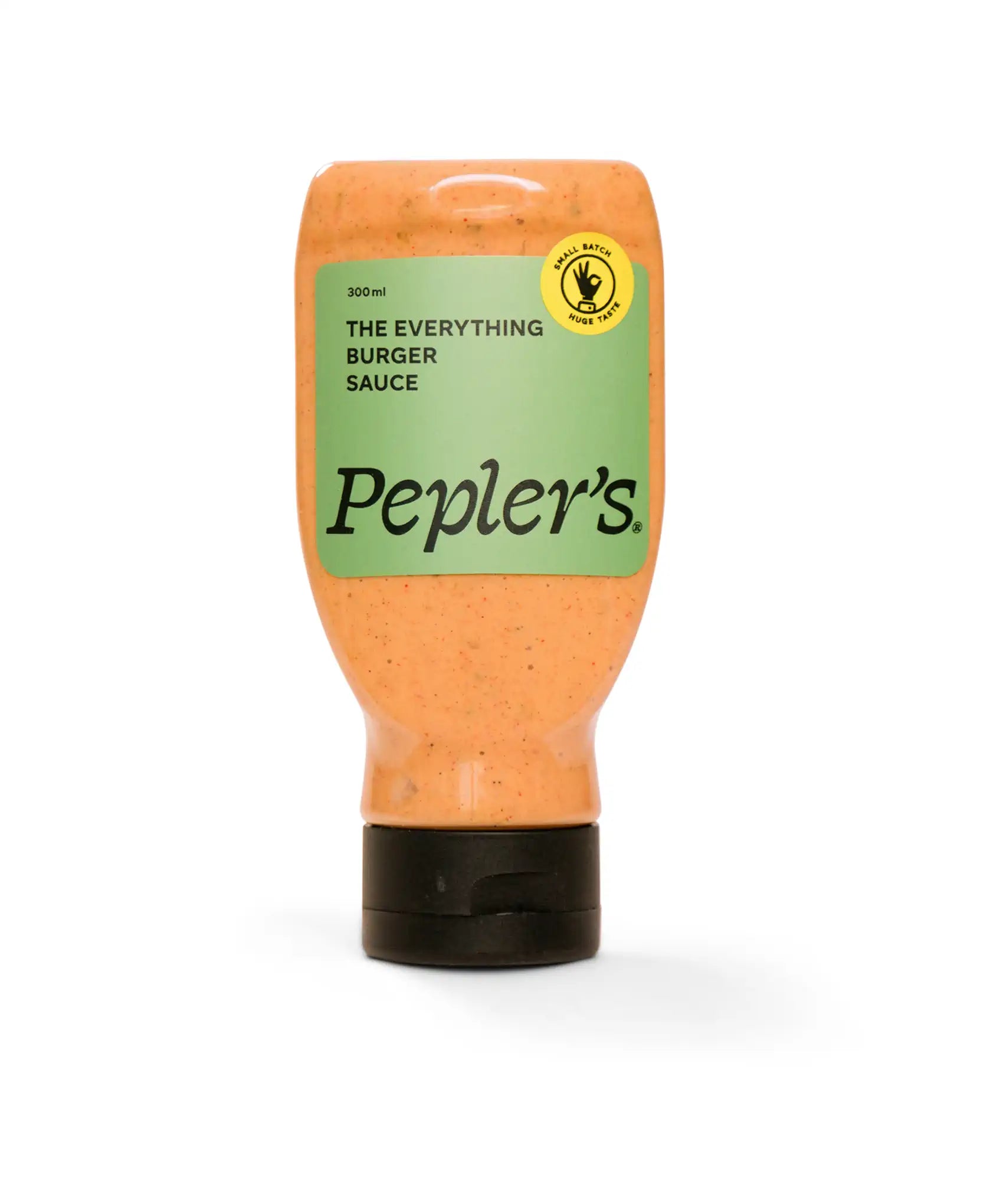 A bottle of Pepler's "The Everything Burger Sauce" featuring a light orange sauce with specks of herbs and spices. The label is predominantly green with bold black text indicating the product name and volume (300ml). There is a yellow circular badge that states "small batch" and "huge taste," emphasising the artisanal nature of the sauce. The bottle has a black flip-top cap and is set against a plain white background.