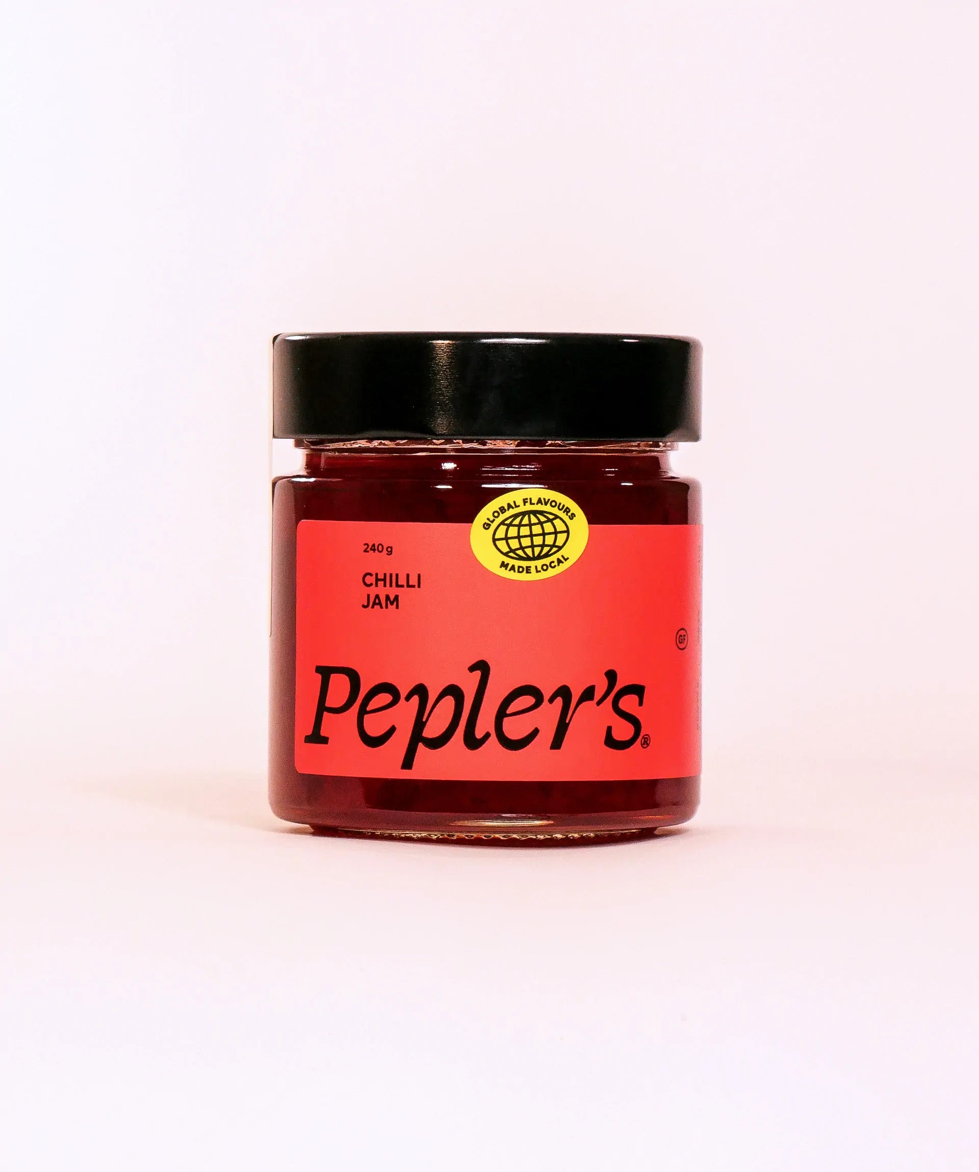 A jar of Pepler's Chilli Jam, featuring a vibrant red label with bold black text stating "Chilli Jam." The jar is sealed with a black lid and includes a yellow sticker with the text "Global Flavours Made Local." The jar contains 240 grams of the jam and is set against a plain white background.