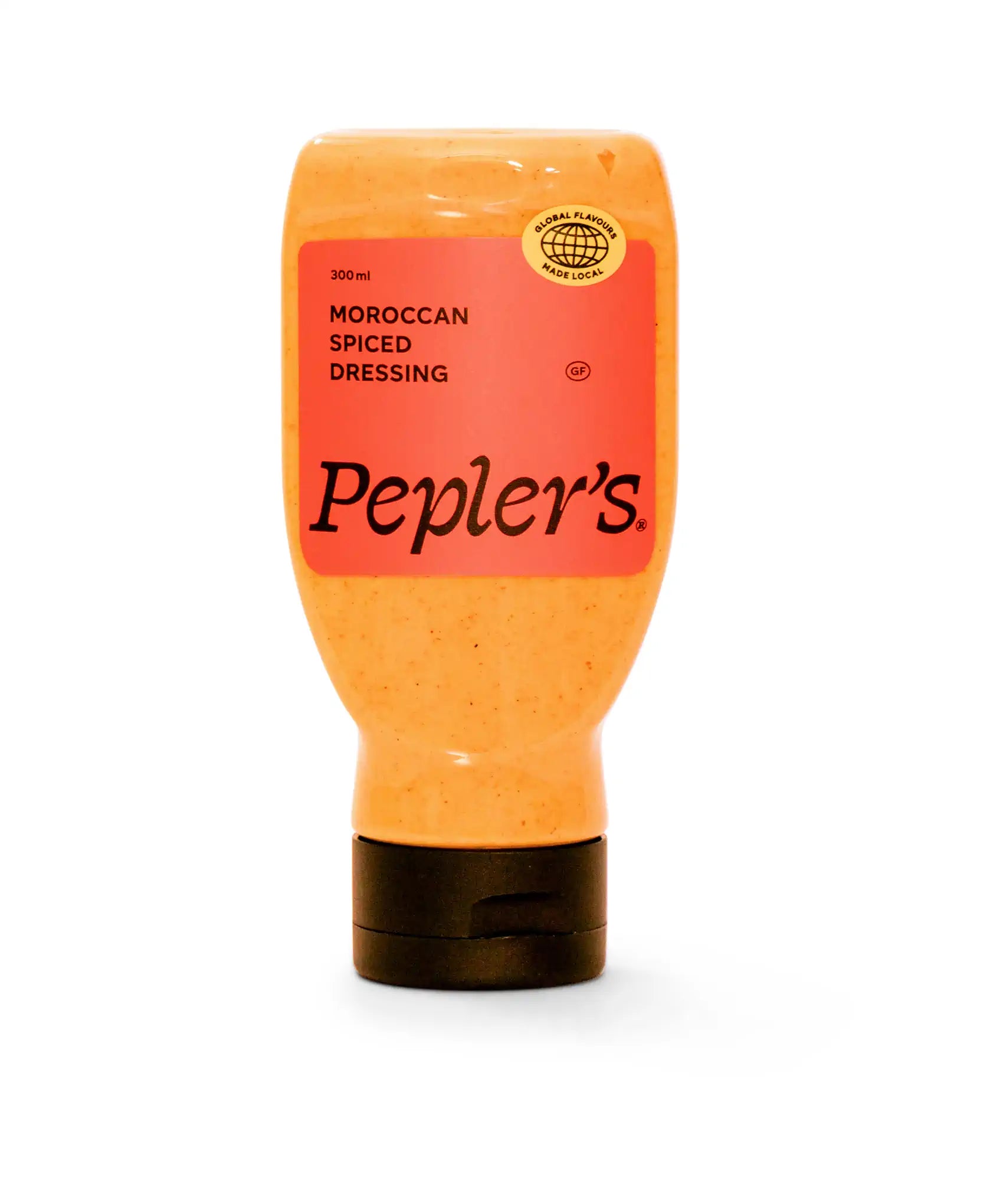 A bottle of Pepler's Moroccan Spiced Dressing, featuring a vibrant orange colour, is displayed against a white background. The bottle stands upright with a black cap, and the label prominently indicates "300 ml" and "Moroccan Spiced Dressing," along with a gluten-free (GF) symbol. A circular logo at the top highlights "Global Flavours Made Local."